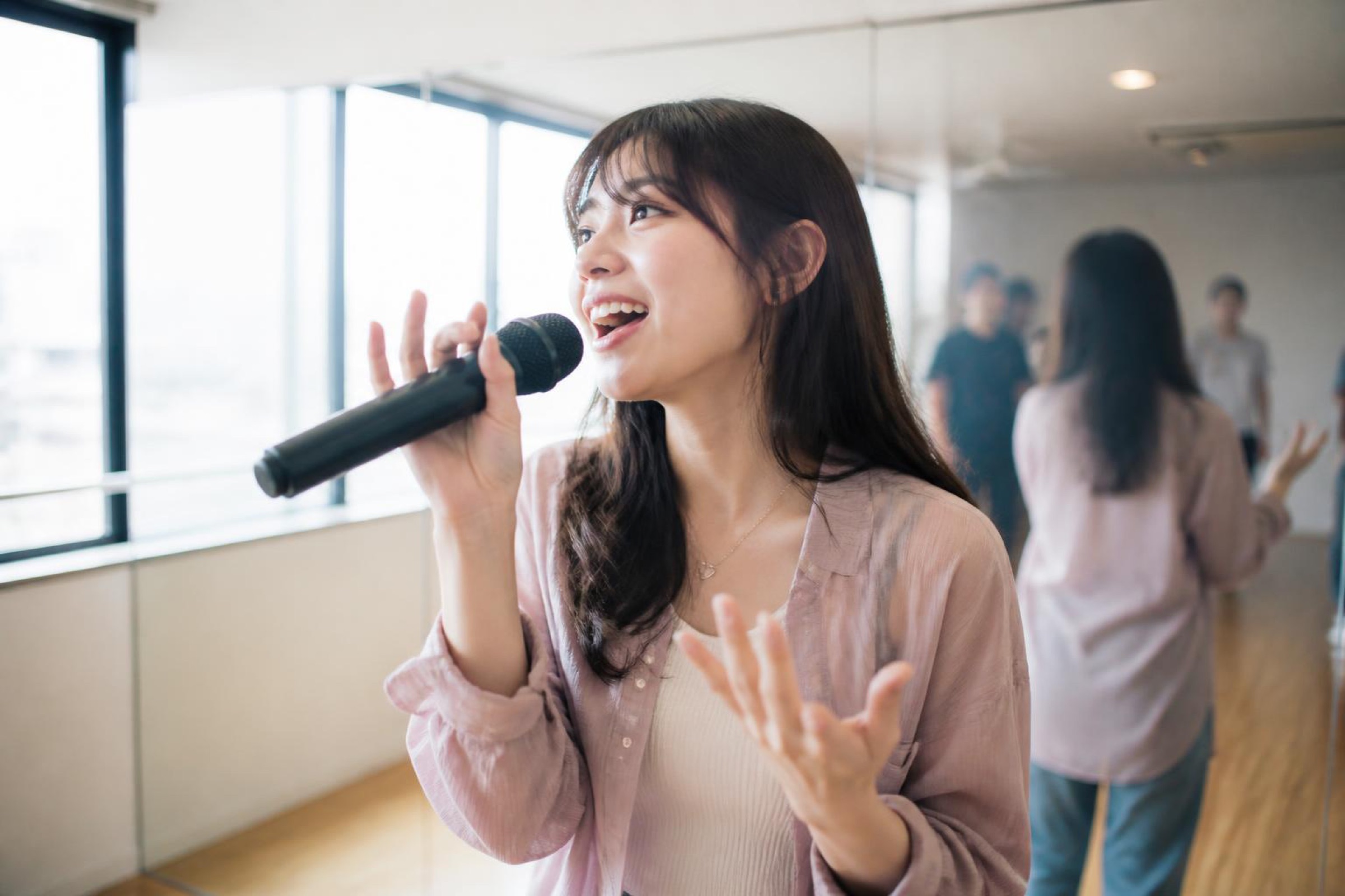 スタジオでマイクを持って歌う女性